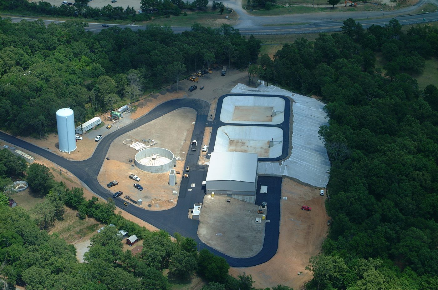 Aerial view of water system construction site with treatment basins and storage tank